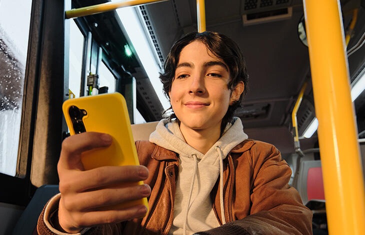 A person looking at their cell phone on the bus