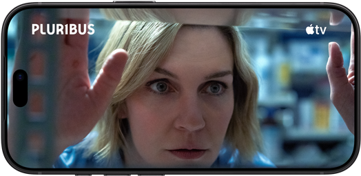 iPhone 18 Pro, landscape mode, displaying a close-up of a woman looking through a window. Series title: Pluribus