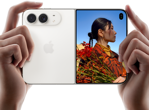 iPhone Duo, Star White colour, held by two hands in horizontal orientation, unfolded, left panel shows 48MP Dual Fusion rear cameras, right panel shows person getting their picture taken on outer display, the subject of the photo is able to see their face as their picture is getting taken using Duo Preview