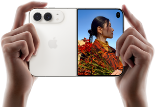 iPhone Duo, Star White colour, held by two hands in horizontal orientation, unfolded, left panel shows 48MP Dual Fusion rear cameras, right panel shows person getting their picture taken on outer display, the subject of the photo is able to see their face as their picture is getting taken using Duo Preview